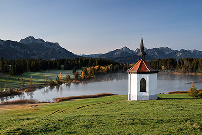 Deutschland, Bayern, Bayerische Voralpen,Ostallgäu, Kapelle am Hegratsrieder See mit Blick in die Allgäuer Alpen