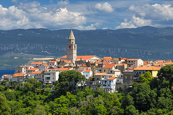 Kroatien, Primorje-Gorski kotar, Kvarner Bucht, Glockenturm der Kirche Mariä Himmelfahrt mit dem Küstengebirge im Hintergrund